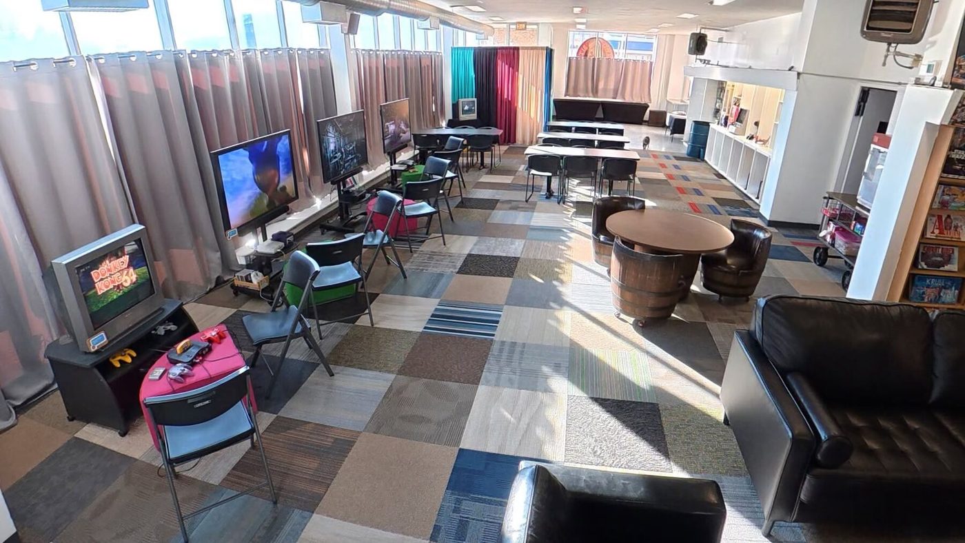 The lounge in daylight with tables, high-top seating, couches and console stations
