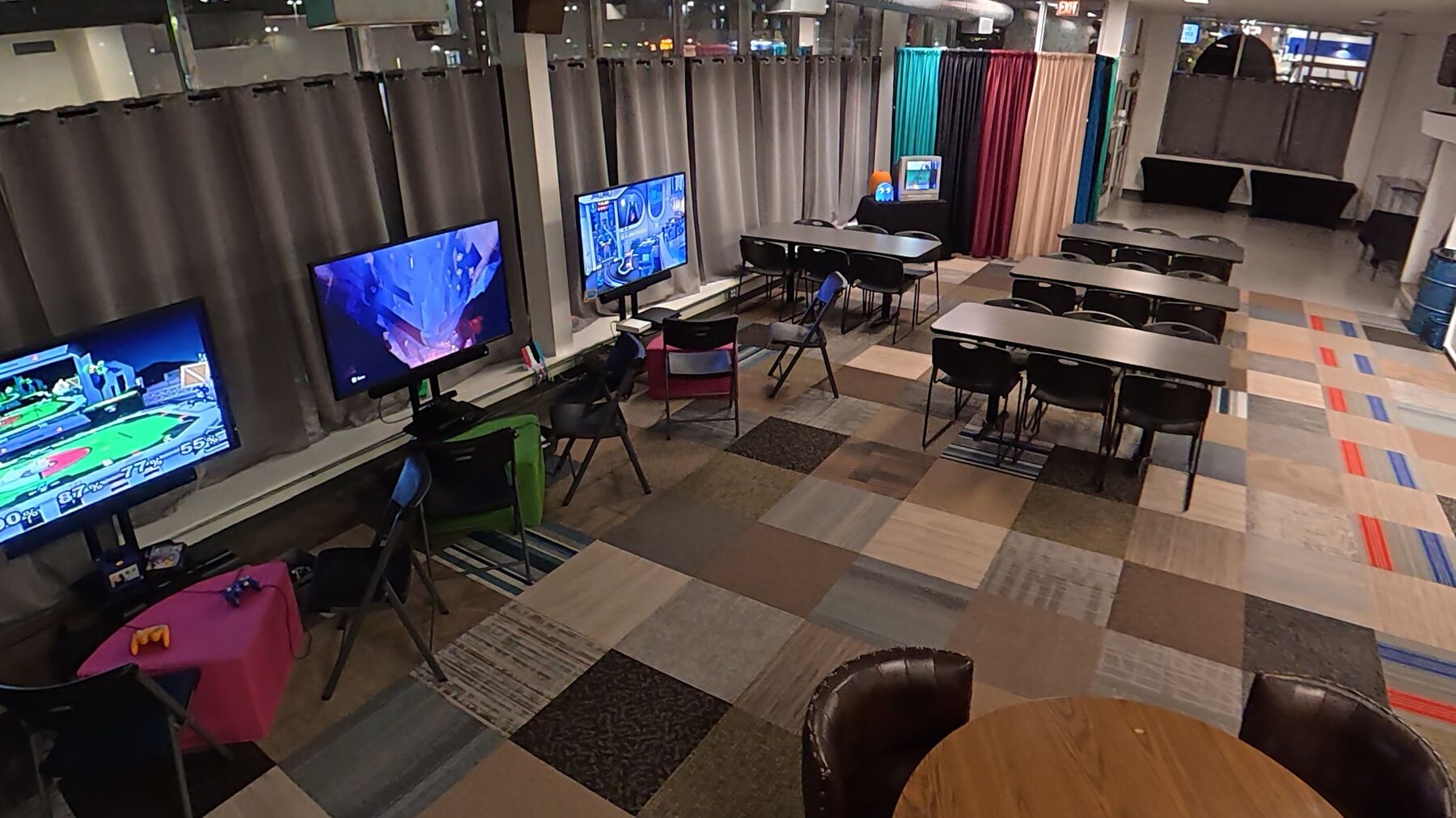 The event lounge with console gaming stations, rows of tables for seating and the serving area along the back wall